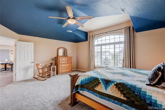 a bedroom with a bed next to a window with a chandelier