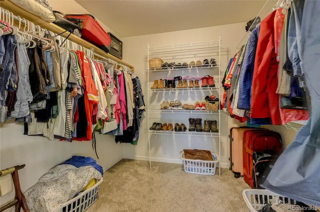 a view of walk in closet with clothes and shoes
