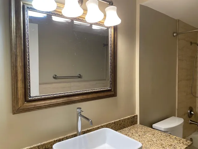 a bathroom with a granite countertop toilet sink and mirror