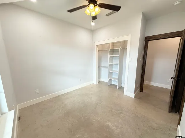 an empty room with closet and a chandelier fan