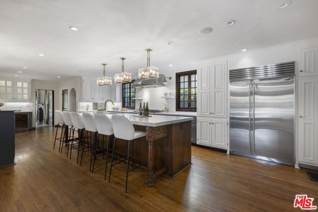 a kitchen with granite countertop a sink dishwasher a dining table and chairs with wooden floor