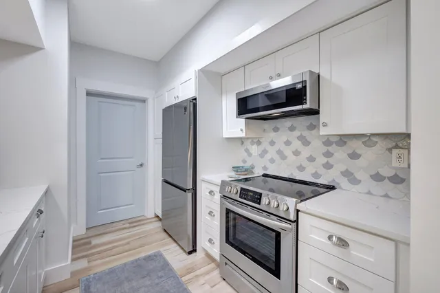 a kitchen with stainless steel appliances white cabinets and a stove top oven