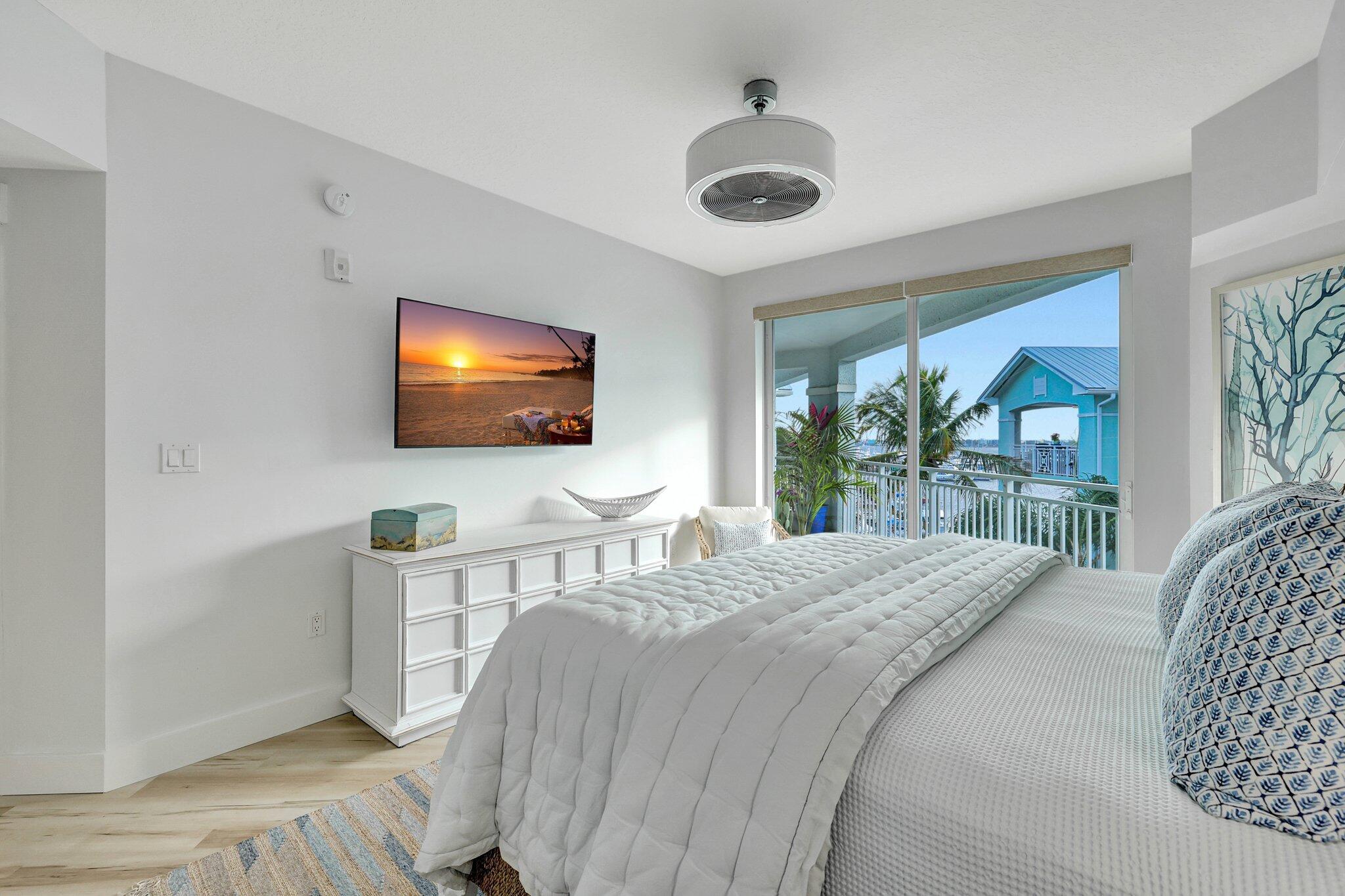 875 Northwest Flagler Avenue, Unit 404 Stuart, FL 34994 - Photo 15 of 56 a bedroom with a bed and a flat screen tv on dresser