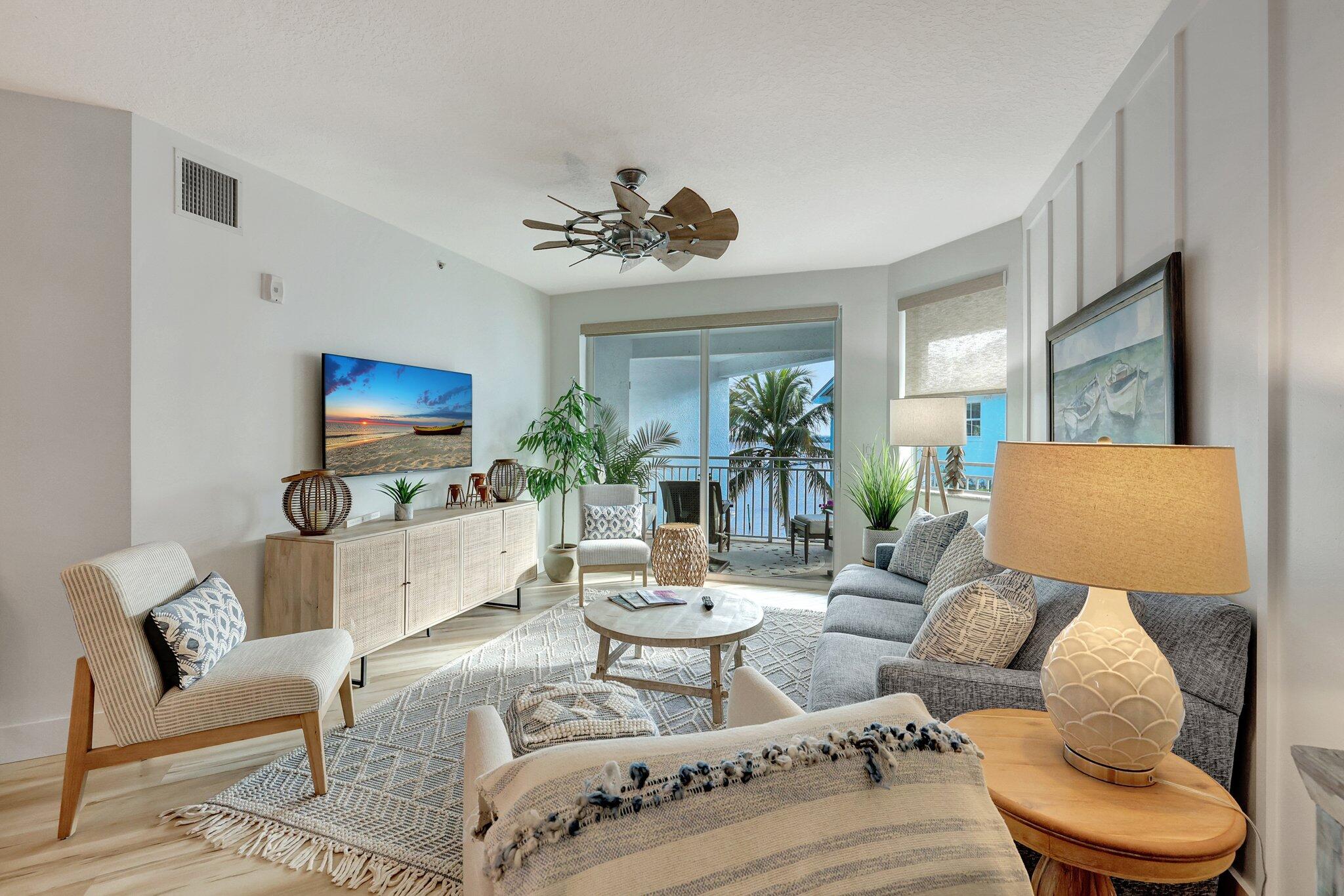 875 Northwest Flagler Avenue, Unit 404 Stuart, FL 34994 - Photo 4 of 56 a living room with furniture a flat screen tv and a large window