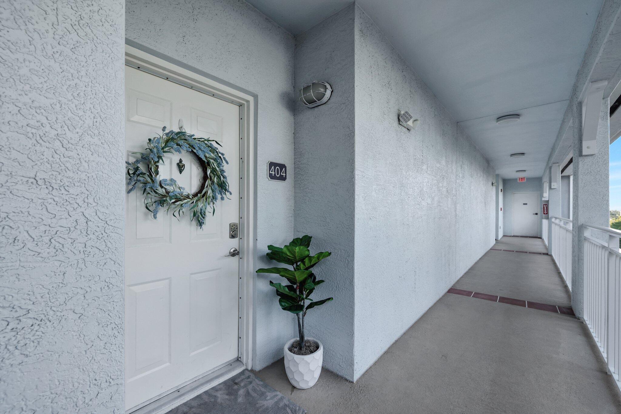 875 Northwest Flagler Avenue, Unit 404 Stuart, FL 34994 - Photo 42 of 56 a view of a hallway with wooden floor and a potted plant