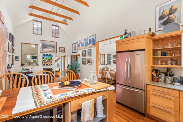 a kitchen with stainless steel appliances granite countertop a dining table chairs and a refrigerator