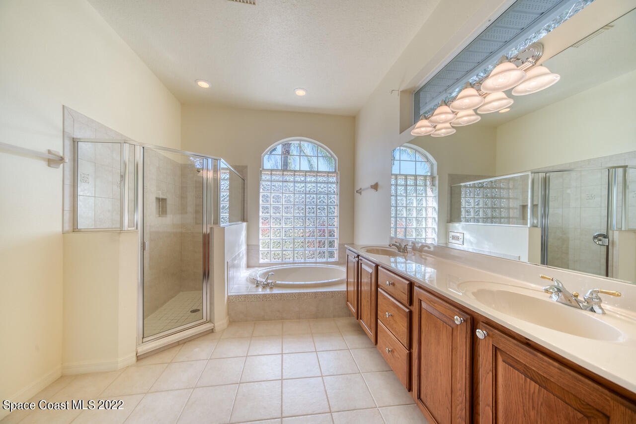 4099 Sparrow Hawk Road Melbourne, FL 32934 - Photo 31 of 48 a spacious bathroom with a double vanity sink a large mirror and a bathtub