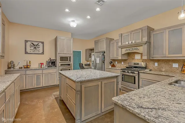 a kitchen with granite countertop a sink stove and refrigerator