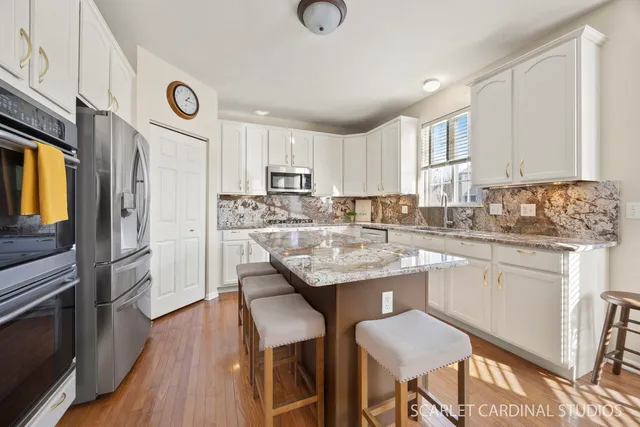 a kitchen with stainless steel appliances granite countertop a table chairs sink refrigerator and cabinets