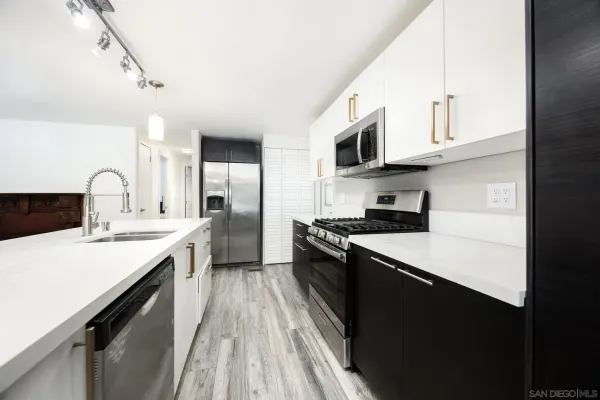 a kitchen with stainless steel appliances a sink dishwasher stove refrigerator and cabinets