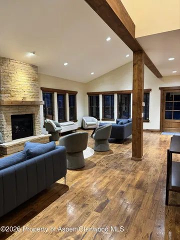 a living room with couches a fireplace kitchen view and a kitchen island