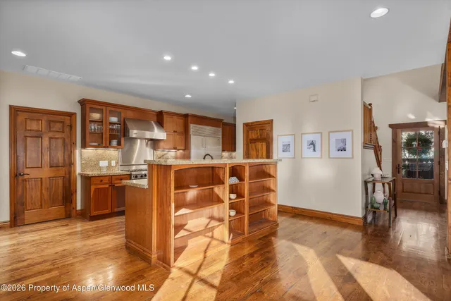 a living room with stainless steel appliances kitchen island granite countertop a refrigerator and cabinets