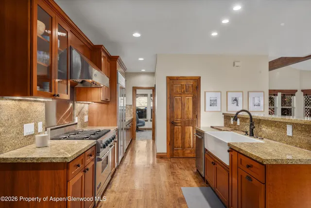 a kitchen with stainless steel appliances granite countertop a sink a stove and a refrigerator