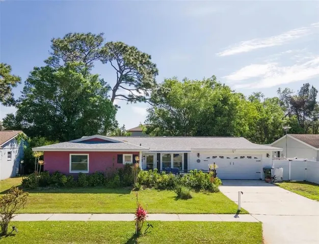 a view of a house with a big yard potted plants and a large tree