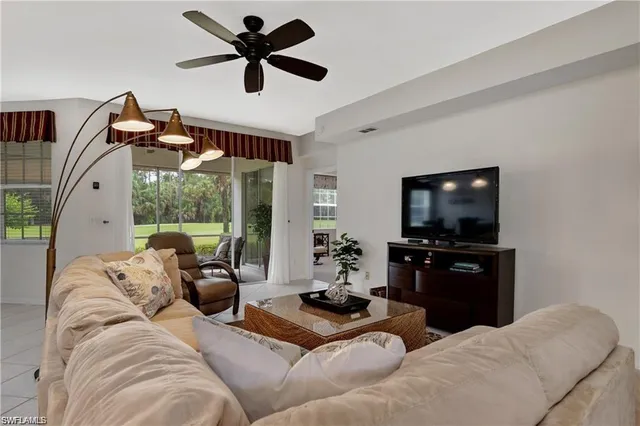 a living room with furniture a flat screen tv and a large window