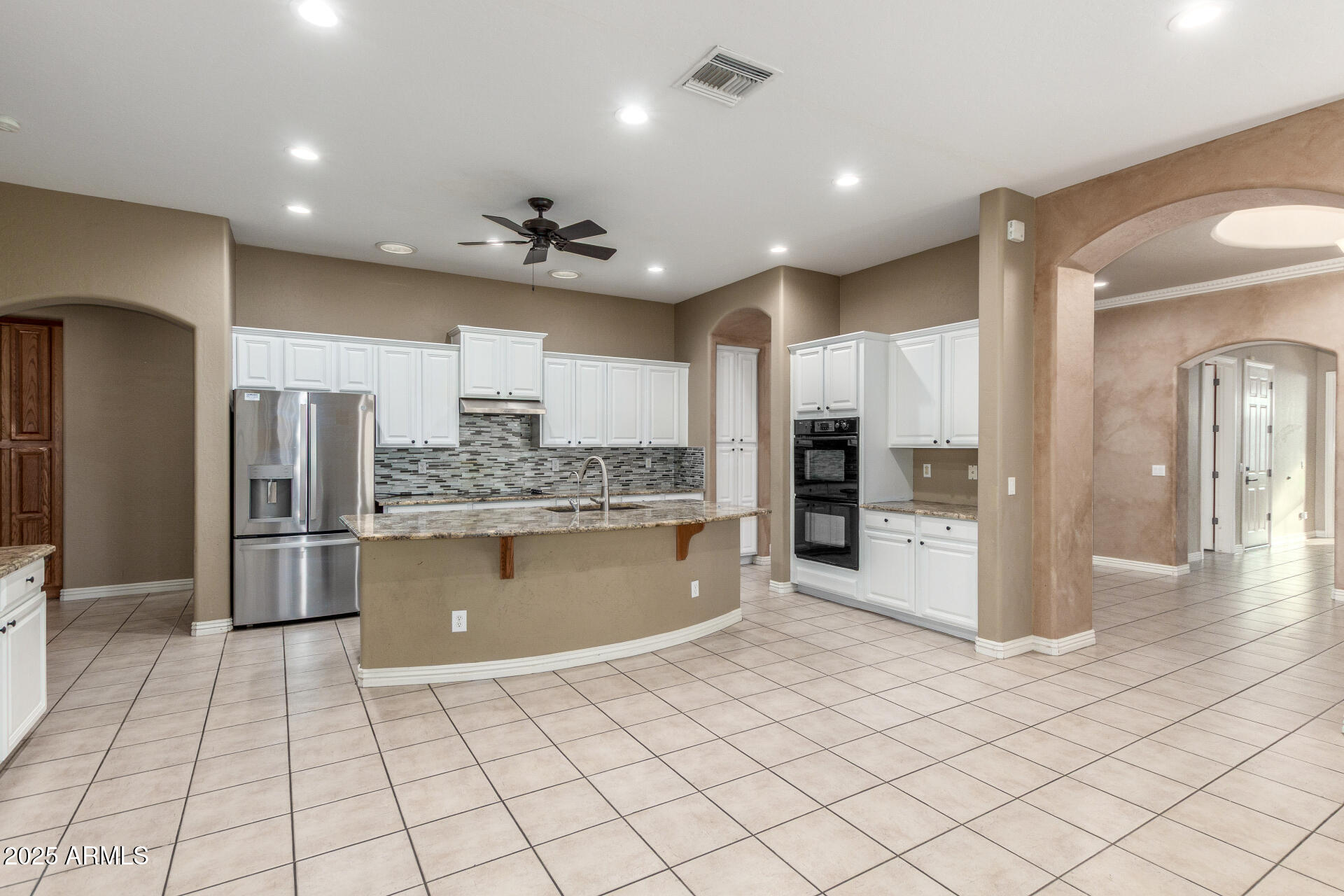 14380 West Monte Vista Road Goodyear, AZ 85395 - Photo 12 of 37 a kitchen with stainless steel appliances kitchen island granite countertop a refrigerator and a sink