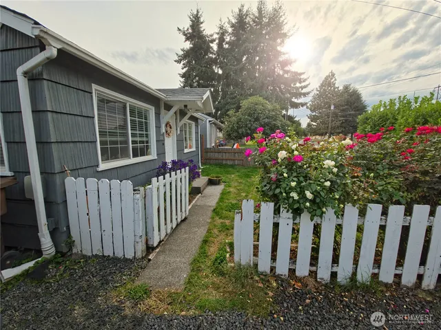 a view of a house with wooden fence and flowers