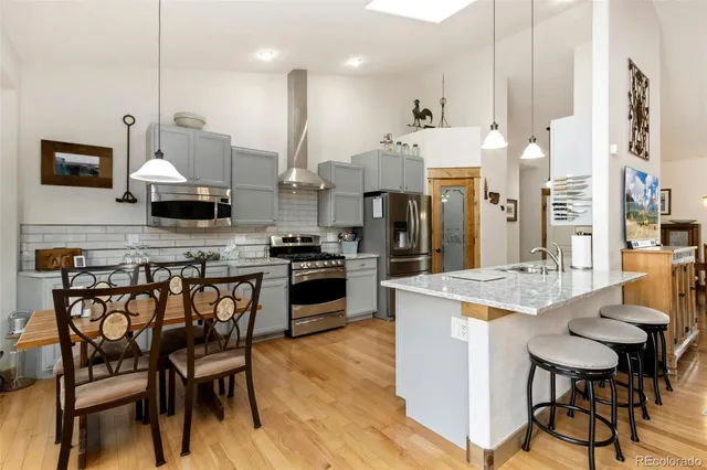 a kitchen with stainless steel appliances a table chairs sink and cabinets