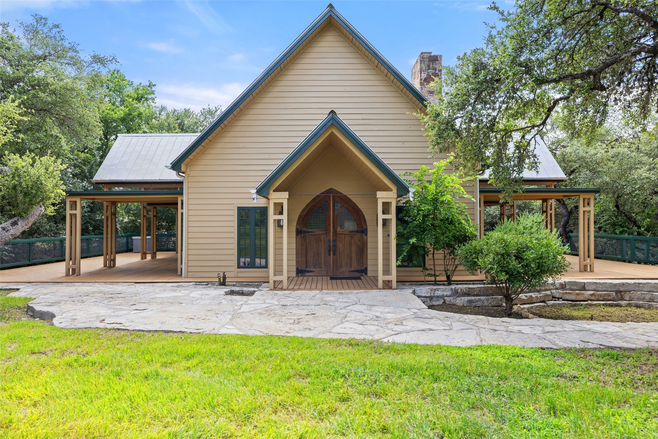 505 Red Corral Ranch Road Wimberley, TX 78676 - Photo 19 of 40 Arched entry doors lead to a charming facade, enveloped by mature trees and a tranquil natural setting.