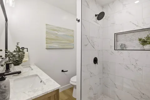 a bathroom with a granite countertop sink a toilet and shower