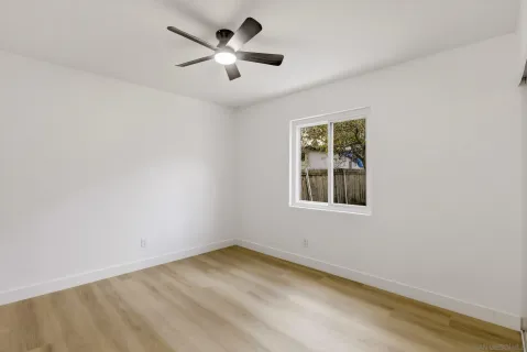 an empty room with a window and a fan