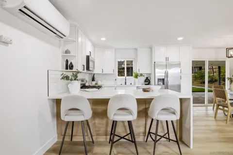 a kitchen with stainless steel appliances kitchen island granite countertop a dining table chairs and white cabinets
