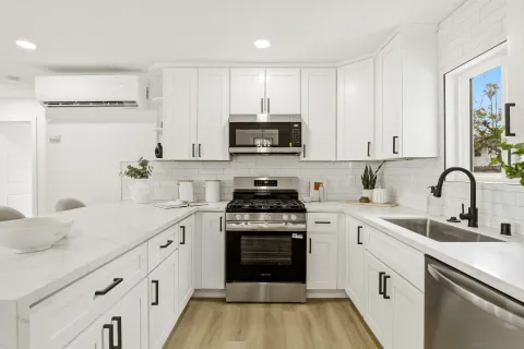 a kitchen with granite countertop white cabinets and stainless steel appliances