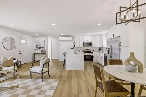 a kitchen with stainless steel appliances kitchen island granite countertop a refrigerator a stove a sink dishwasher with a dining table and chairs with wooden floor