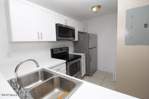 1021 Abada Court Northeast, Unit 102 Palm Bay, FL 32905 - Photo 8 of 16 a kitchen with a sink and a refrigerator