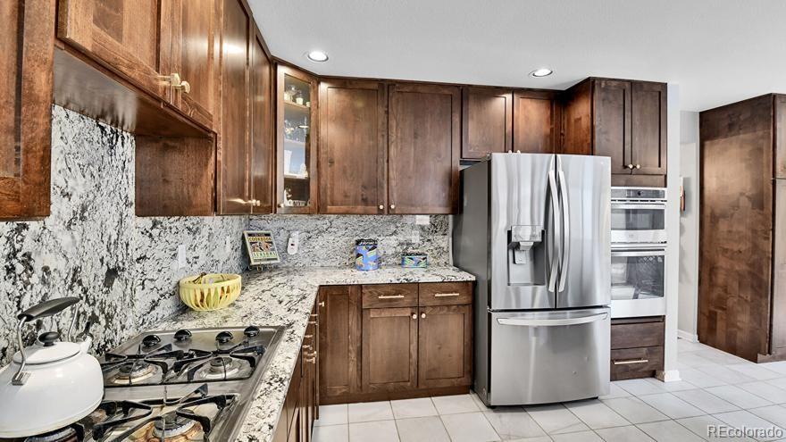 4852 South Carson Street Aurora, CO 80015 - Photo 19 of 48 a kitchen with stainless steel appliances granite countertop a refrigerator and a stove top oven