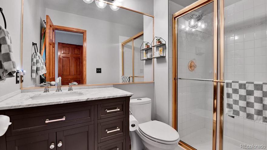 4852 South Carson Street Aurora, CO 80015 - Photo 34 of 48 a bathroom with a granite countertop sink toilet a mirror and shower