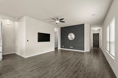 a view of an empty room with a window and wooden floor