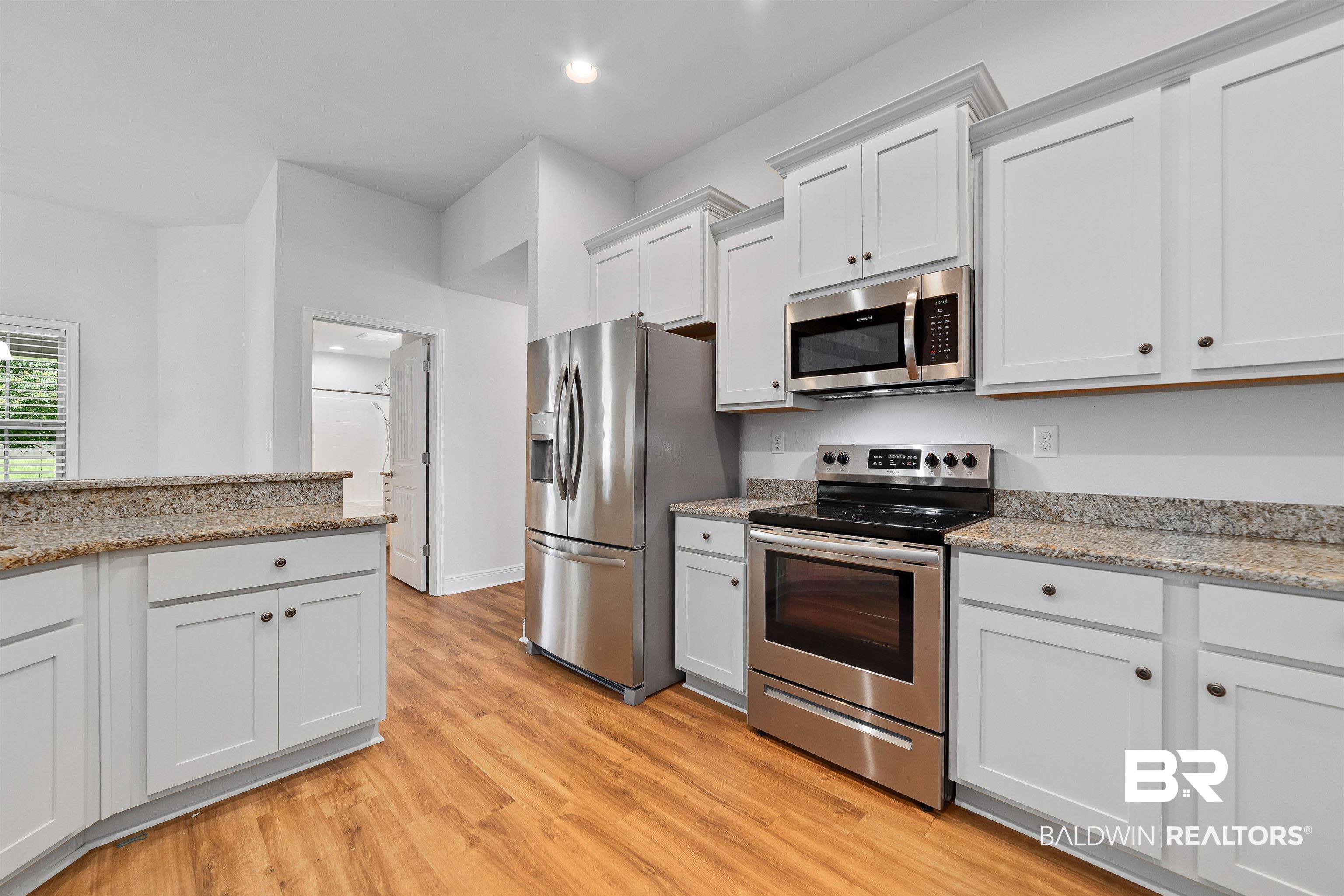 13155 Wishbone Court Foley, AL 36535 - Photo 14 of 39 Kitchen featuring white cabinetry, stainless steel appliances, light hardwood / wood-style flooring, and light stone counters