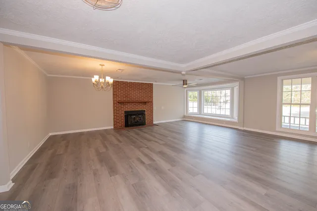 an empty room with wooden floor fireplace and windows