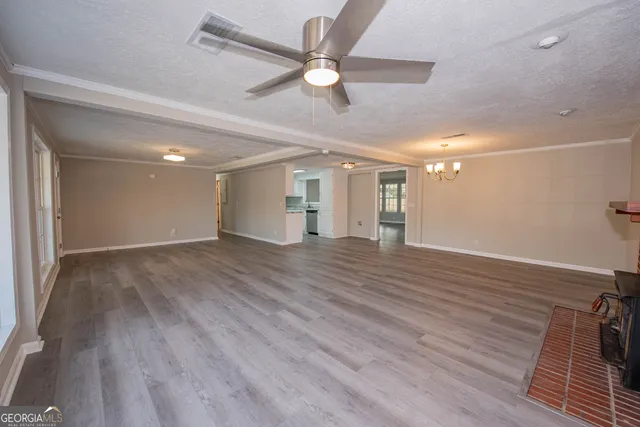 a view of an empty room with wooden floor and a ceiling fan
