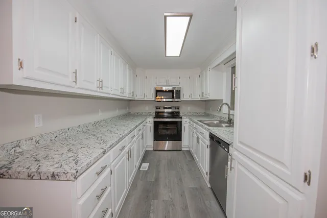 a kitchen with granite countertop white cabinets and stainless steel appliances