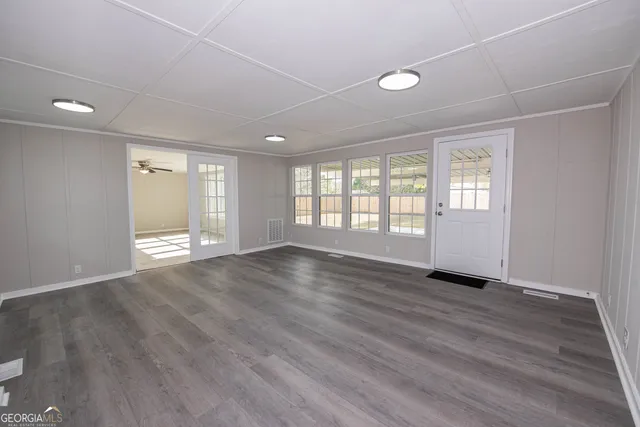 an empty room with wooden floor and windows