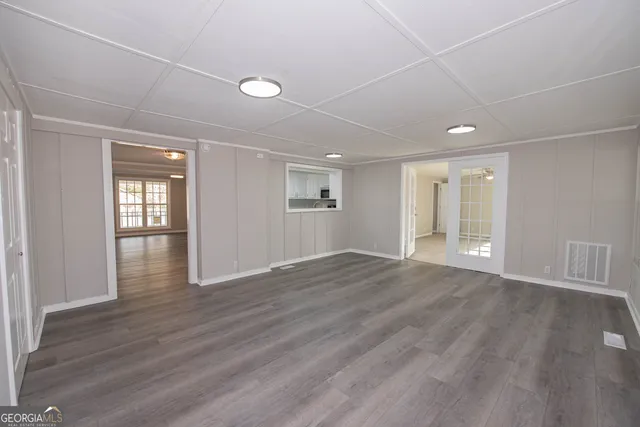a view of an empty room with wooden floor and windows