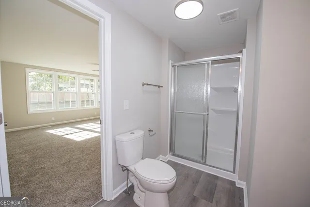 a bathroom with a granite countertop toilet a sink and a window