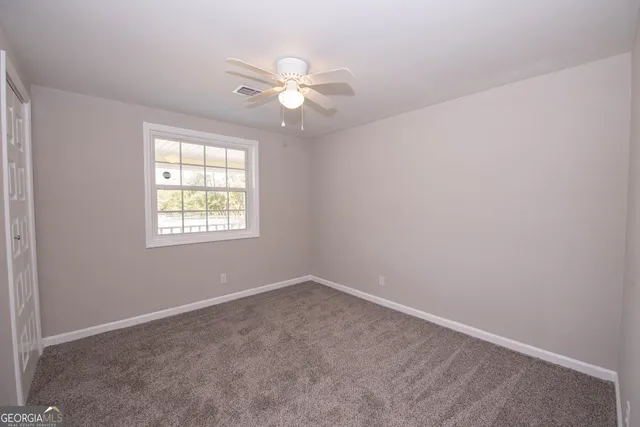 an empty room with windows and fan