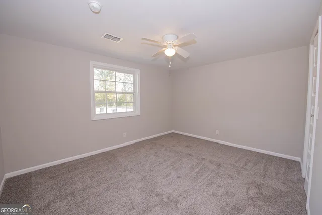 an empty room with windows and fan