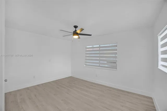 a view of a room with wooden floor and a ceiling fan