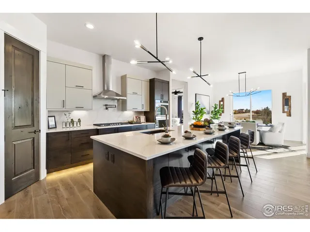 a kitchen with stainless steel appliances kitchen island granite countertop a sink a stove a refrigerator and island with wooden floor