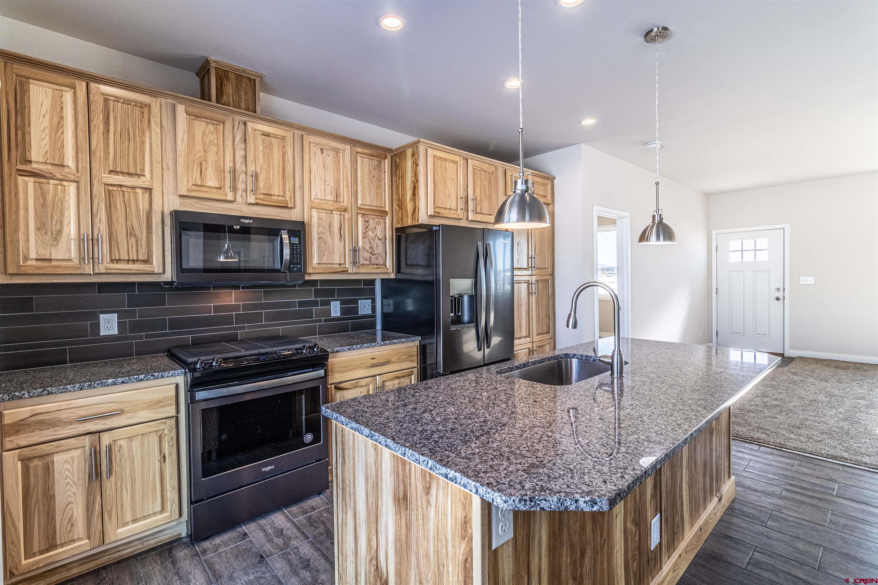 200 Chesterfield Place Ignacio, CO 81137 - Photo 11 of 35 a kitchen with kitchen island granite countertop a stove top oven a sink dishwasher and microwave with wooden floor