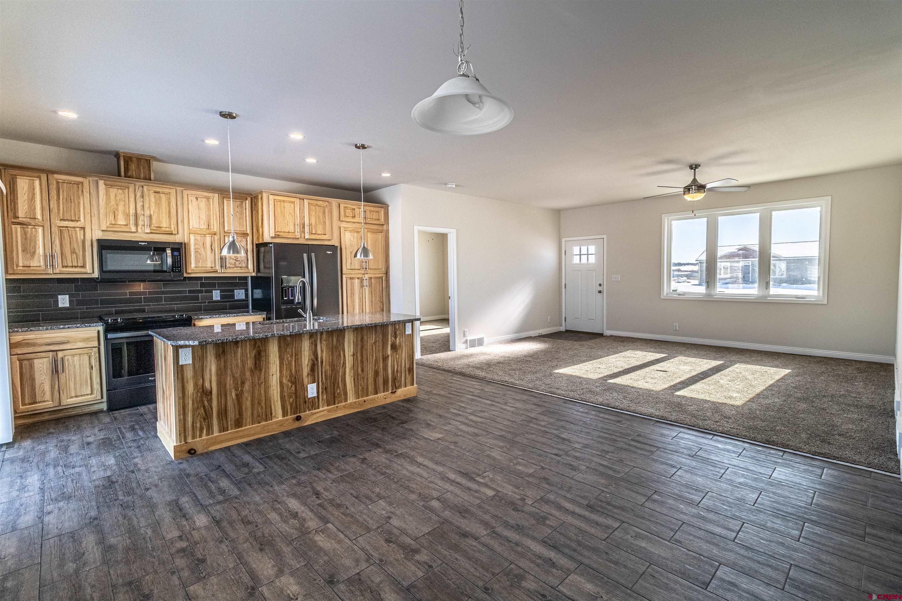 200 Chesterfield Place Ignacio, CO 81137 - Photo 13 of 35 a kitchen with stainless steel appliances granite countertop a stove a sink a refrigerator white cabinets and wooden floor next to a window