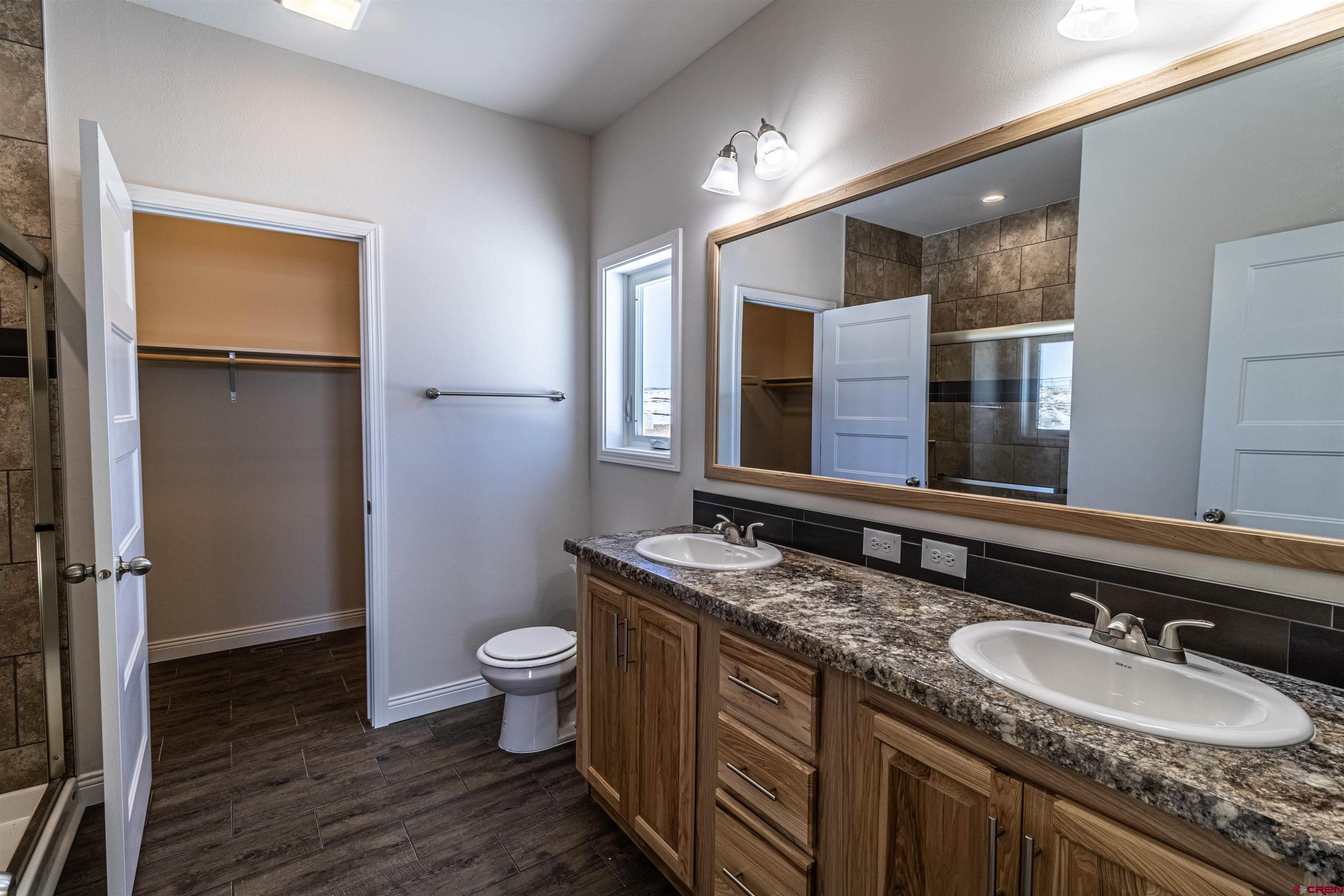 200 Chesterfield Place Ignacio, CO 81137 - Photo 18 of 35 a bathroom with a granite countertop sink a toilet a mirror and shower