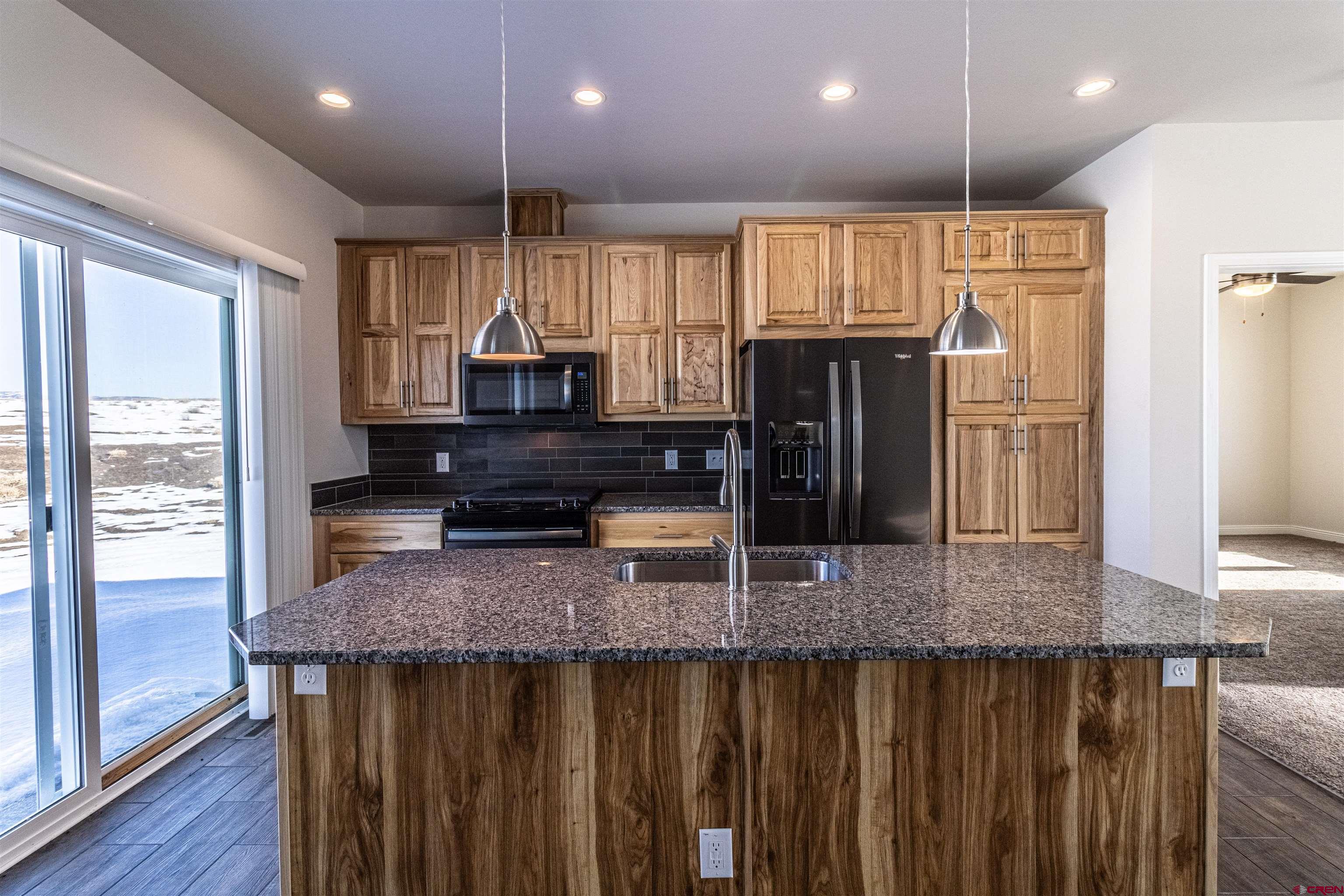200 Chesterfield Place Ignacio, CO 81137 - Photo 10 of 35 a kitchen with kitchen island granite countertop wooden cabinets and refrigerator