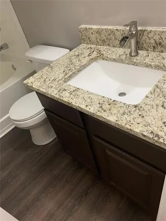 a bathroom with a granite countertop sink and toilet