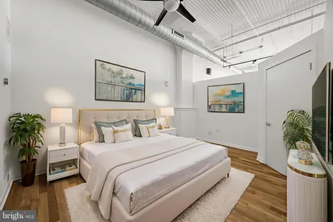 a bedroom with a large bed a potted plant and dresser
