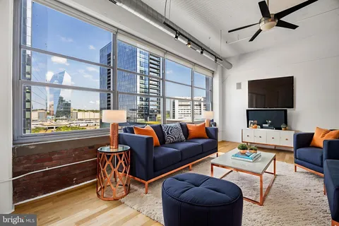 a living room with furniture a flat screen tv and a floor to ceiling window
